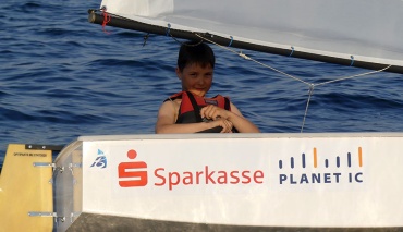 Junge im Segelboot Optimist
